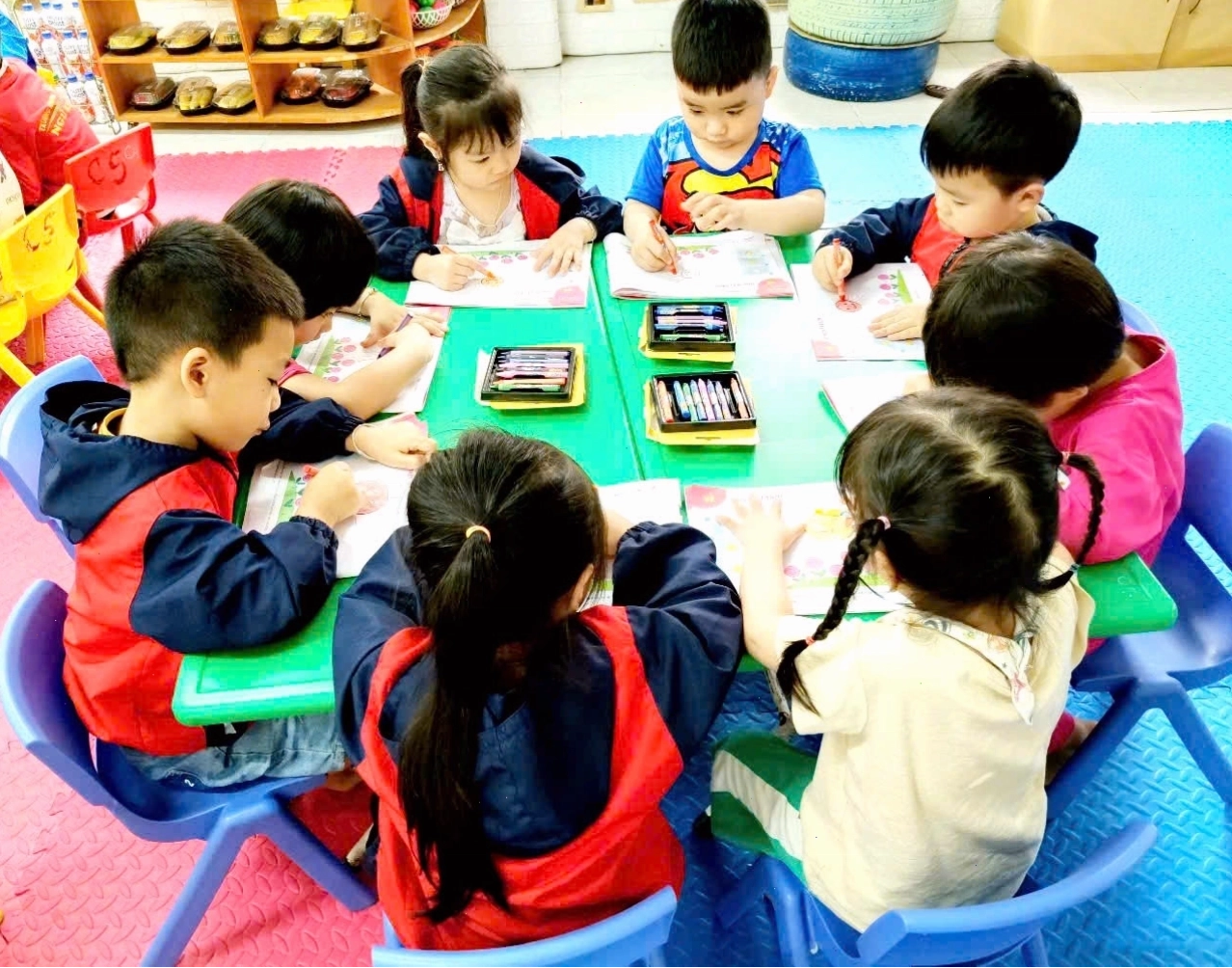 Bé đang tập vẽ ông mặt trời hoạt hình với bút màu