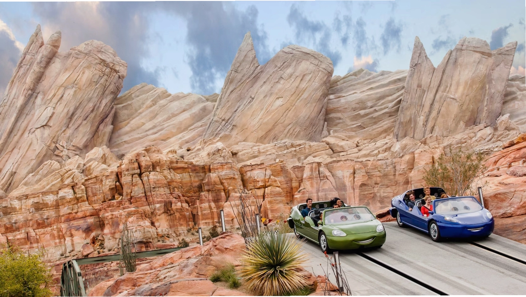 Hai chiếc xe với khách tham quan đang đua trên cảnh quan sa mạc tại Radiator Springs Racers